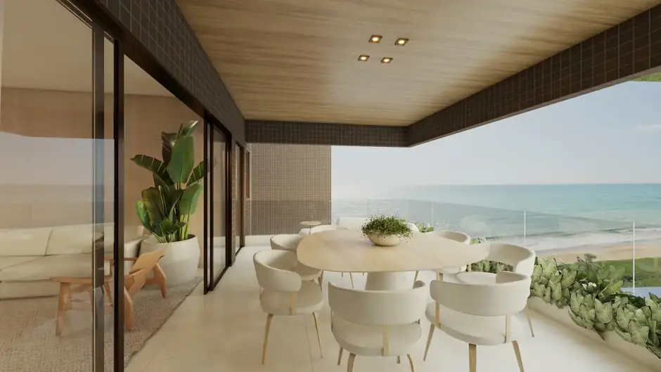 Varanda do apartamento lateral com mesa de jantar e vista para a praia